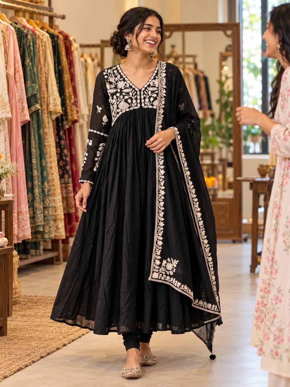 A woman in an embroidered silk anarkali sharing a candid laugh in a warm boutique